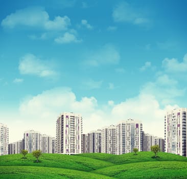 High-rise buildings of same design over grassy hills with a few trees.