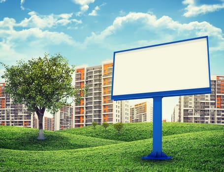 Blank billbord and tree against high-rise buildings over green hills with a few trees