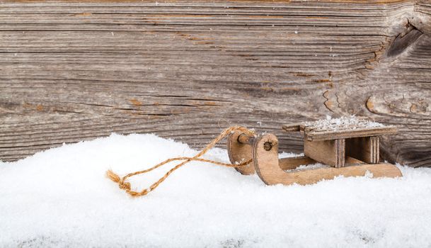 old rustic wooden sledge, over snow, wooden background