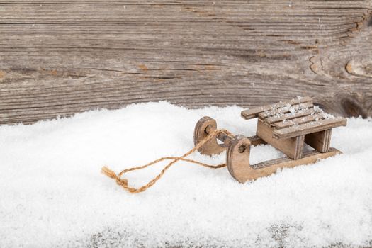 old rustic wooden sledge, over snow, wooden background