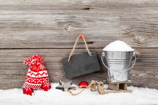 Snow in a bucket on a sled, on wooden background, with Christmas decoration