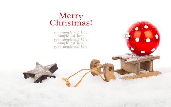 red polka dot Christmas bauble on old rustic wooden sledge over snow, isolated over white background