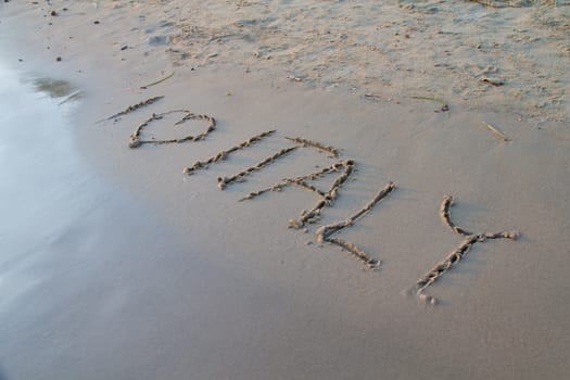 Photo shows a detail of the sign in the beach sand.