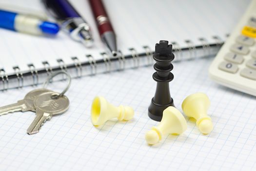 Photo shows keys, chess figurines, paper block and pencils on a business table.