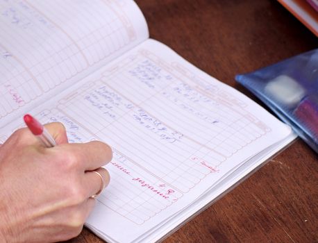 teacher's hand  makes note in school diary