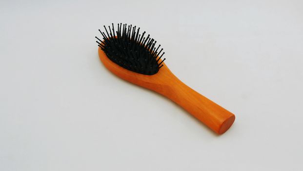 Comb with handle made of brown wood placed on white background.                               