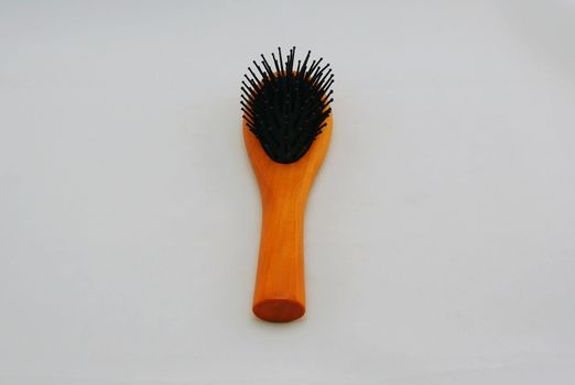 Comb with handle made of brown wood placed on white background.                               