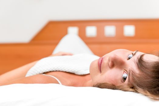 smiling young beauty girl in bed under the covers