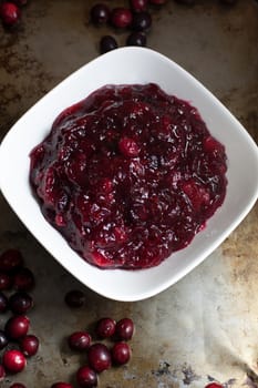 Fresh, rustic cranberry sauce in a white bowl on a dark metal surface.