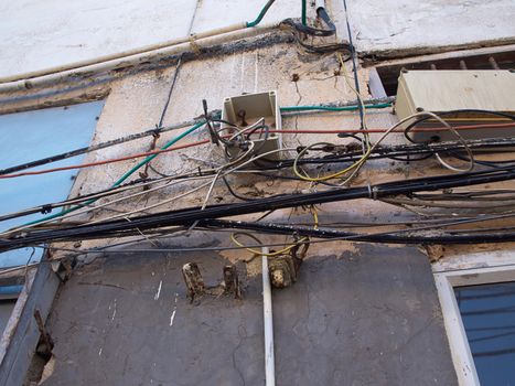 Tangled electric cable mess on a wall of building