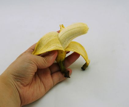 Woman holding a ripe banana with yellow shell out half.                         