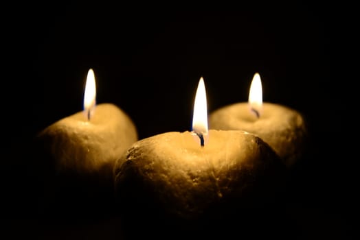 Photo of three candles isolated on a black background. Objects photography.