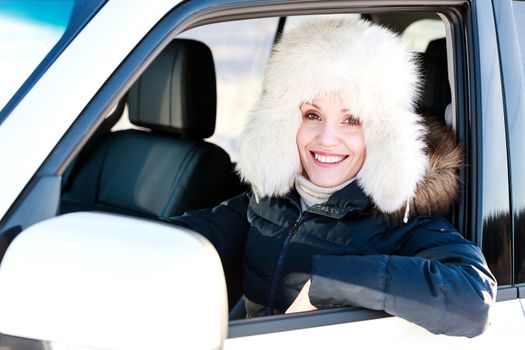 Pretty woman in white fur hat in a car