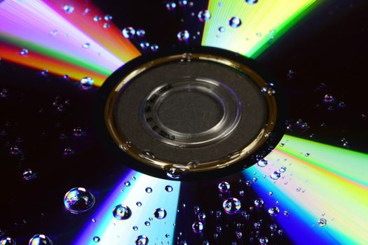 Photo of a compact disc with water drops isolated on black background. Objects photography.
