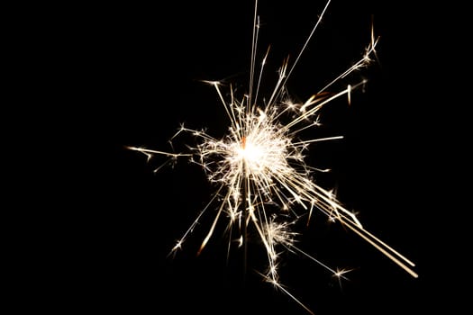 Photo of a burning christmas sparkler isolated on black background. Objects photography.