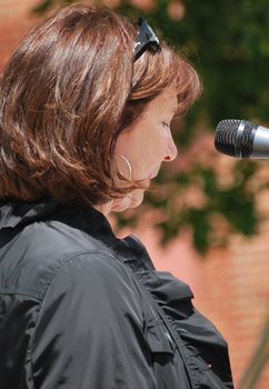 Masters of ceremony speaking to an audience outside.