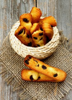 Arrangement of Biscuit Raisin Cookies in Wicker Bowl on Sackcloth closeup on Rustic Wooden background