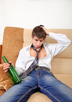 Teenager with Bottle of the Beer on the Sofa at the Home