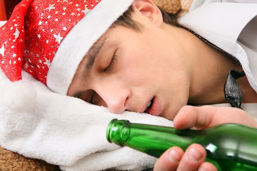 Drunken Teenager sleeping in Santa Hat and Bottle of the Beer on the Sofa