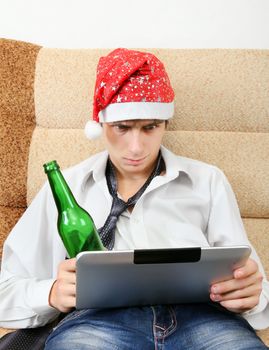 Troubled Teenager in Santa Hat with Tablet Computer and Bottle of the Beer