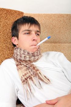 Sick Teenager with Thermometer on the Sofa at the Home