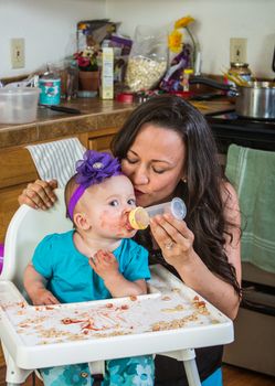 A woman in the kitchen feeds her baby from bottle