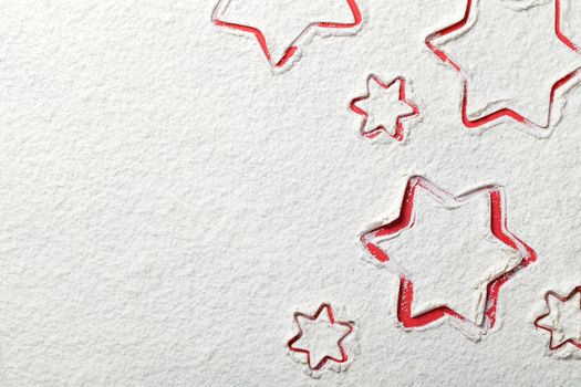 Christmas stars on flour background. White flour looks like snow. Top view