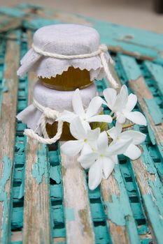 Jasmine honey and jasmine blossoms on an old wooden surface