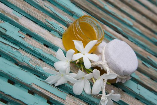 Jasmine honey  in an opened glass and jasmine blossoms on the old wooden surface