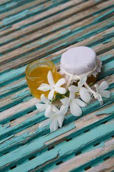 Jasmine honey  in an opened glass and jasmine blossoms on the old wooden surface