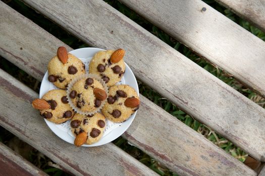 A plate of mini shortcakes with chocolate chips and almond nuts on the wooden surface. Top view
