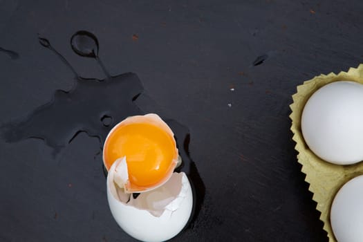 A broken egg on a black wooden surface