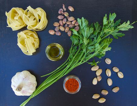 Ingredients for preparing pasta with pistachio pesto on a black wooden surface. Top view. Background