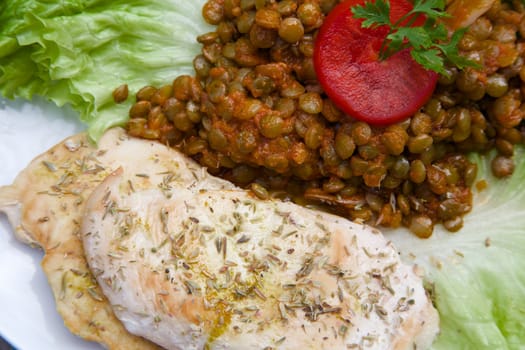 Fitness lunch - stewed green lentils in the tomato sauce with garlic and grilled chicken fillet with oregano. Close up. Top view