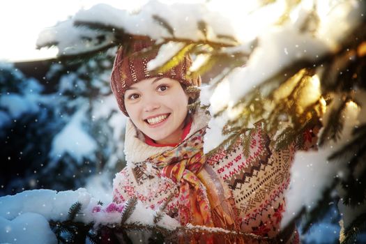 Portrait of the beautiful girl near a fir-tree in the winter wood