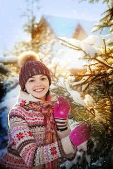 Portrait of the beautiful girl with a fir-tree branch in hands in the winter wood