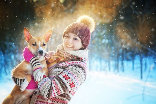 Portrait of the beautiful girl with a dog in the winter wood