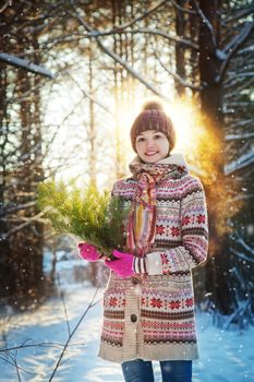 Portrait of the beautiful girl with a fir-tree branch in hands in the winter wood