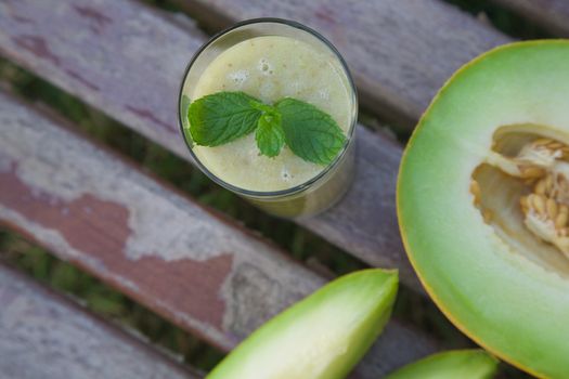 A glass of melon smoothie on an old wooden surface. Top view