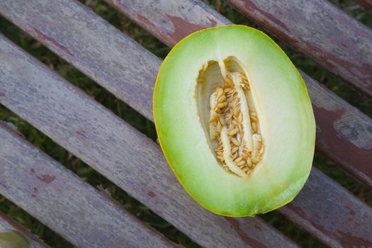 A half of green melon with seeds on old wooden surface. Top view