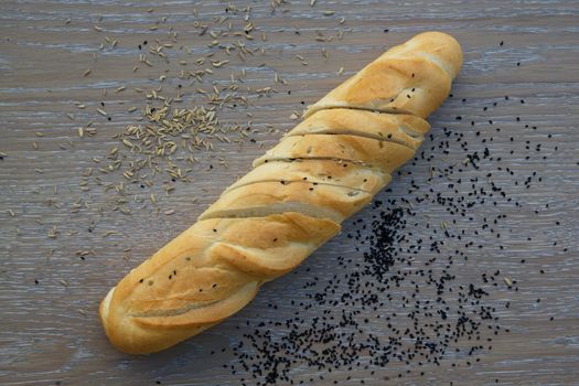 White French baguette with fennel seeds and black seed grains on a wooden surface