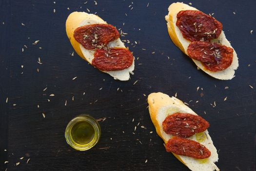 Flavorful starter - sun-dried red tomatoes with oregano and olive oil on the pieces of French baguette