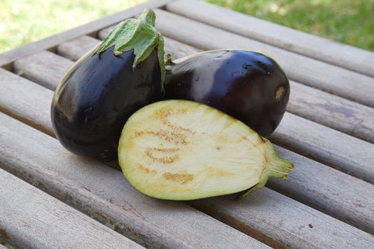 Two and one half eggplants on an old wooden surface
