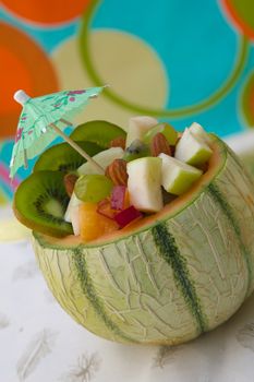Vitamin dessert- fruit salad in the honeydew melon skin. Decorated by paper umbrella