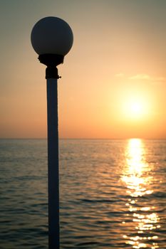Golden sunset on a sea with silhouette of a lantern