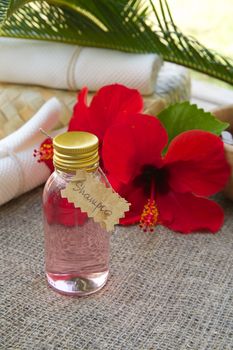 A bottle of hibiscus shampoo. Flowers of hibiscus in the background