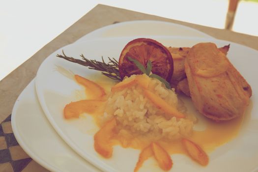 Healthy balanced lunch- chicken rice in orange sauce with rosemary. Decorated with rosemary twig and dried orange slice