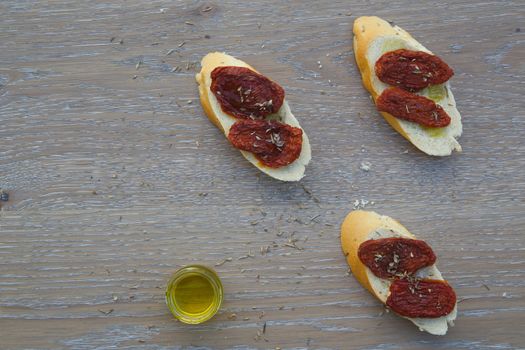 Flavorful starter - sun-dried red tomatoes with oregano and olive oil on the pieces of French baguette