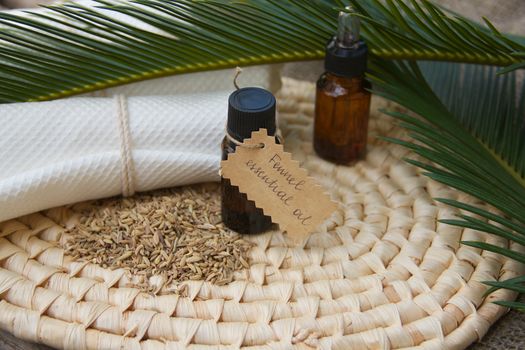 A dropper bottle  of cardamom essential oil. Fennel grains in the background