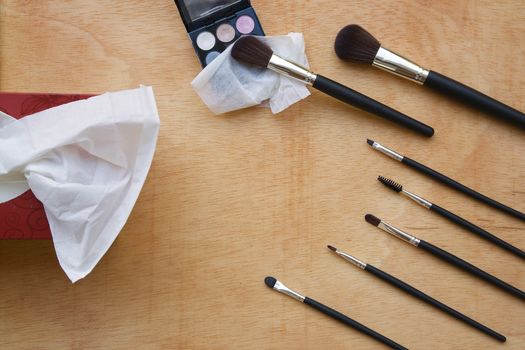 Makeup brushes set, makeup palette,handkerchiefs on a wooden surface.Top view. Background